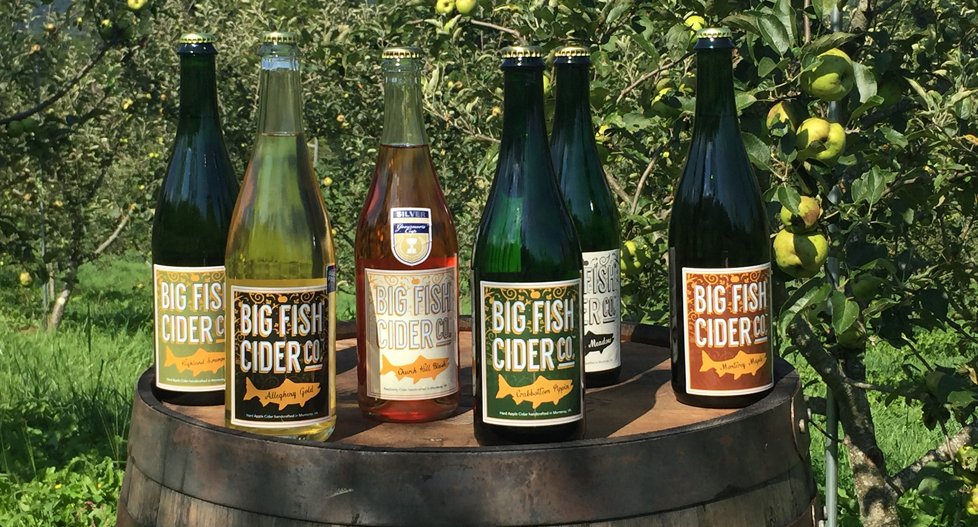 Bottles of Big Fish Cider sitting on top of a barrel in the orchard